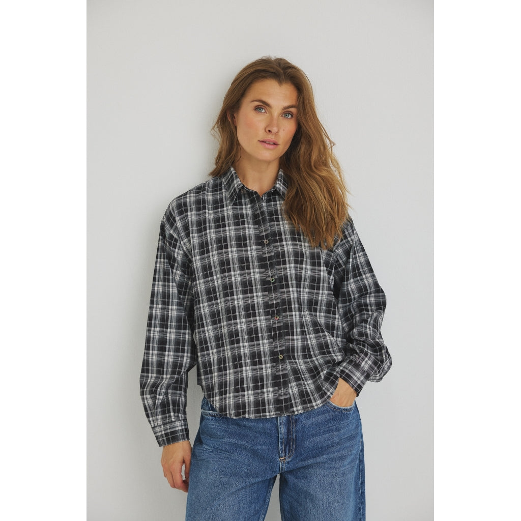 Kvinde iført en sort og hvid 156413 | Luxzuz - Zerafine Ternet-ternet skjorte og blå jeans.