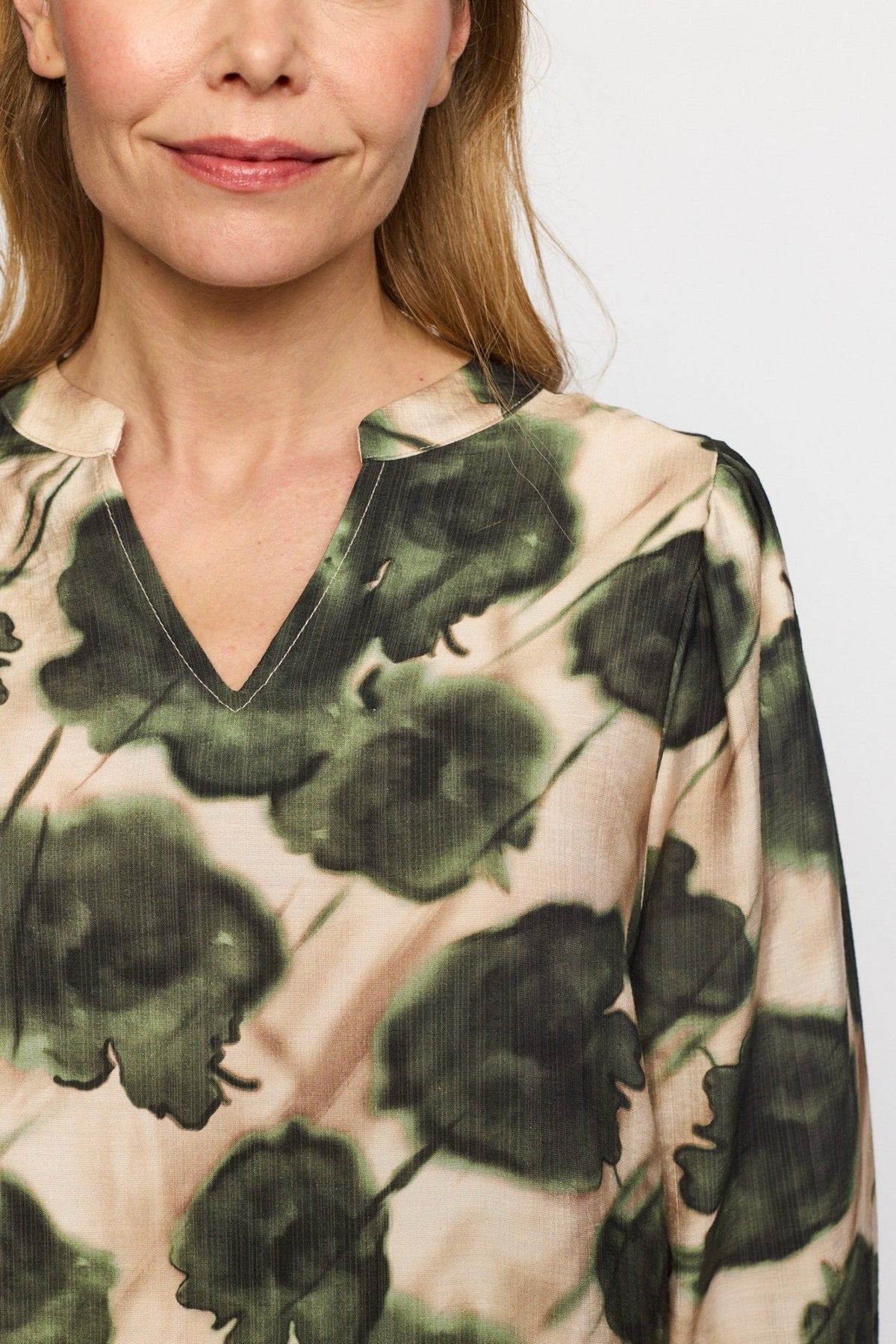 Kvinde iført en 2-Biz Lisa Grøn-bluse med grønt og beige blomstermønster, der står med ansigtet fremad, hvor ansigtet er delvist synligt.