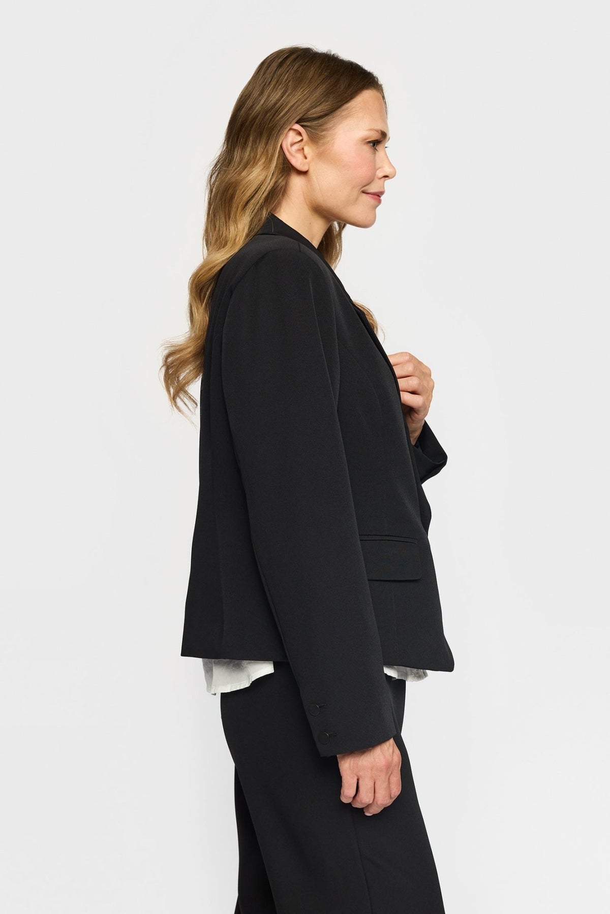 Profilbillede af en kvinde, der bærer en sort 2-Biz – Judith Sort-blazer over en hvid top.