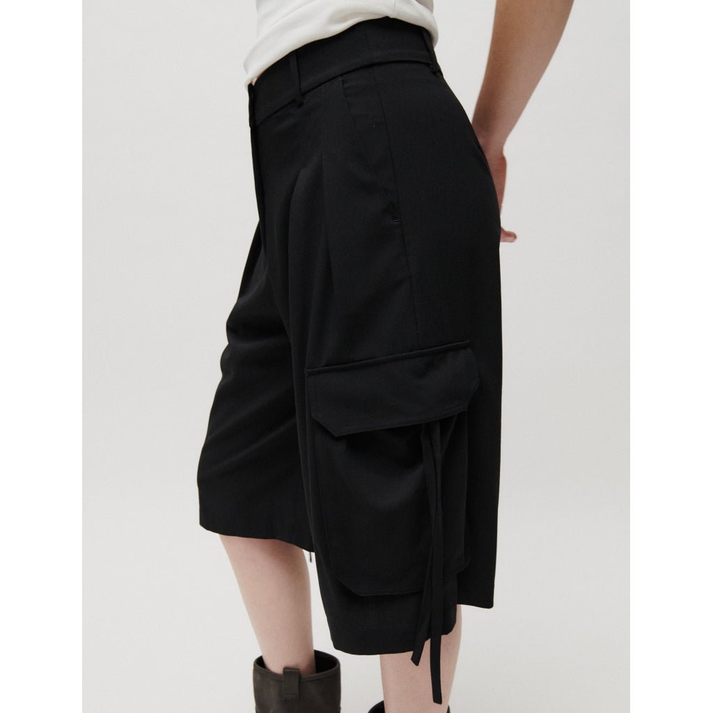 Person iført 2NDDAY Hattori Sort-shorts, hvid top og sorte støvler, set fra siden.