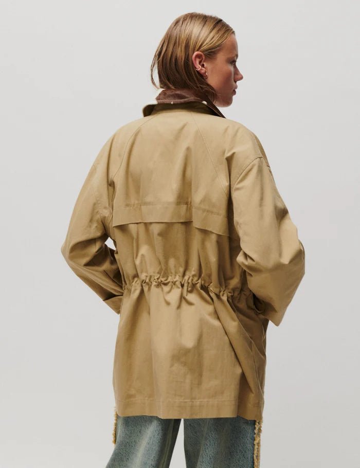 En person set bagfra i en 2NDDAY Spencer Khaki-jakke i tanfarve med justerbar talje, foran en ensfarvet lys baggrund.
