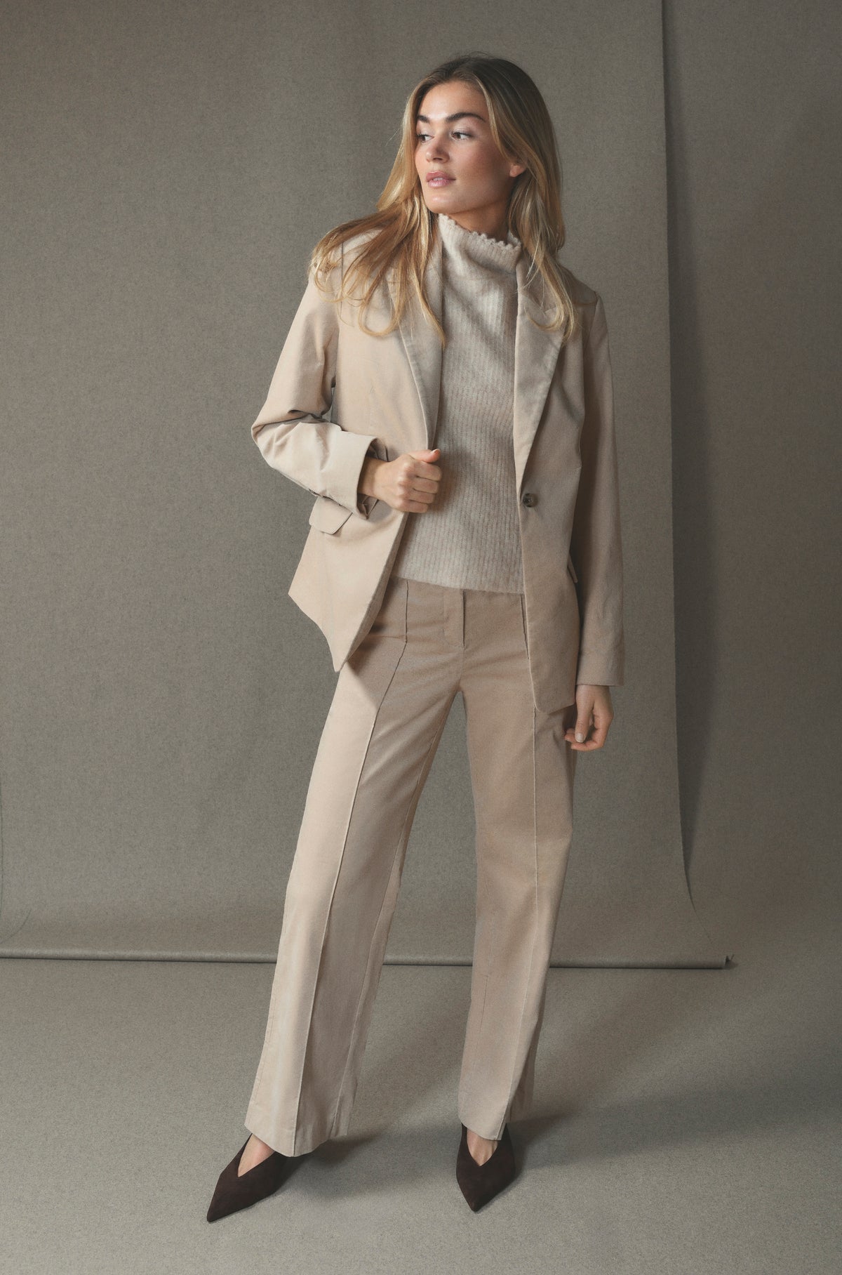En person iført en 156409 | Gustav - Stacie Beige-blazer, matchende sweater og bukser samt mørke sko med spids snude.
