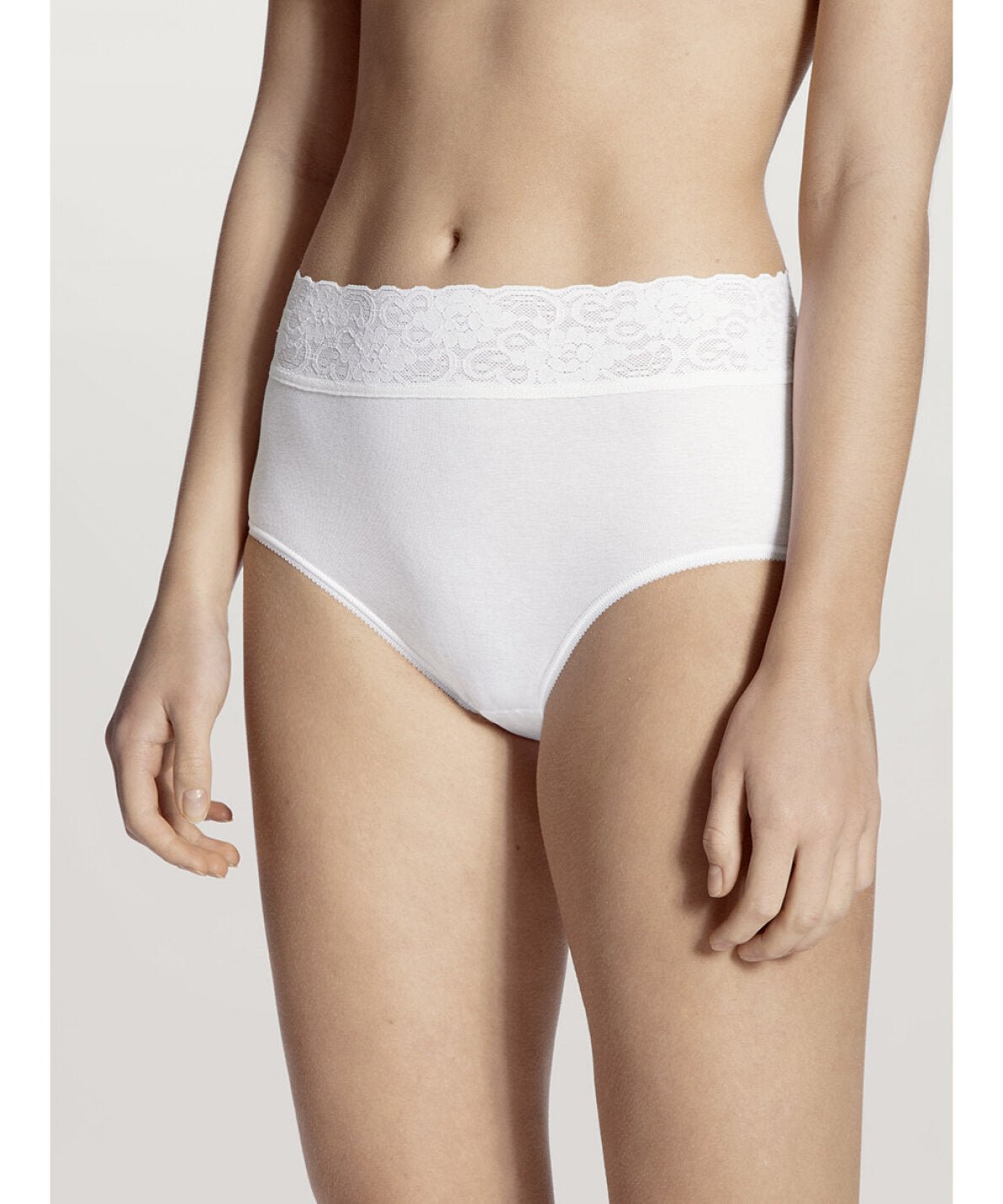 En model bærer Calida 125979 Lycraspitze Hvid, et par hvide trusser med høj talje og blondekant i linningen, foran en neutral baggrund.
