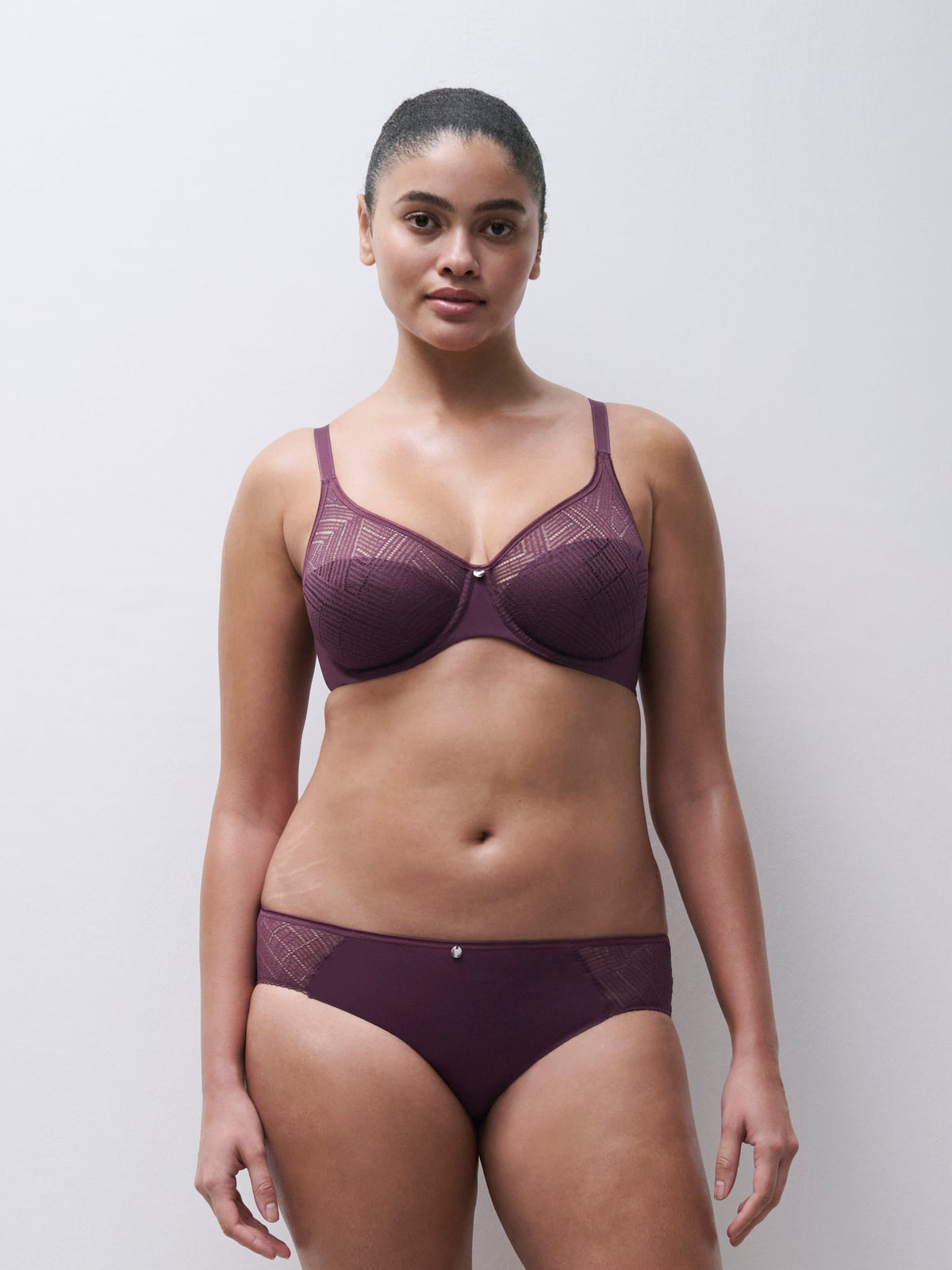 Kvinde iført en Chantelle EasyFeel Emma Plum Bordeaux-bh og trusser med grafisk blonder på en ensfarvet baggrund.