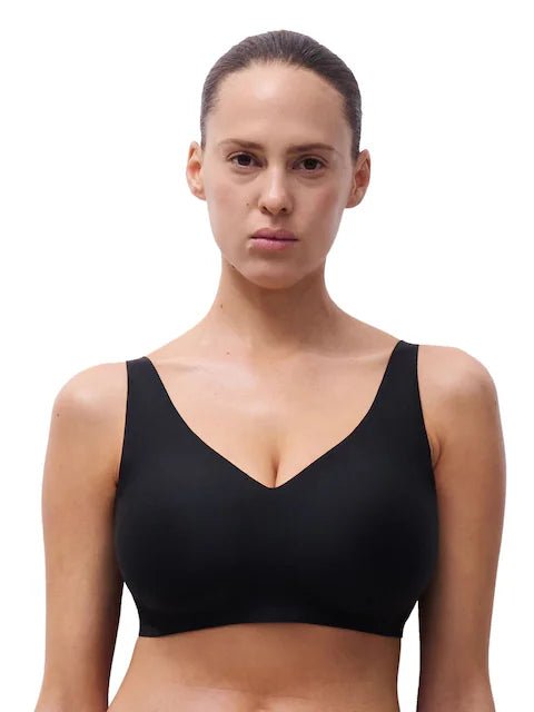 En kvinde iført en Chantelle Seamless Soft Stretch Power Sort-bh, der står med ansigtet vendt fremad foran en ensfarvet hvid baggrund.