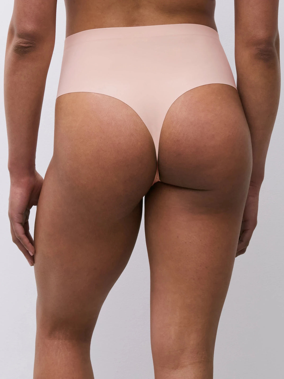 En person iført en Chantelle Seamless - Defi Pudder-g-streng, set bagfra på en ensfarvet baggrund.