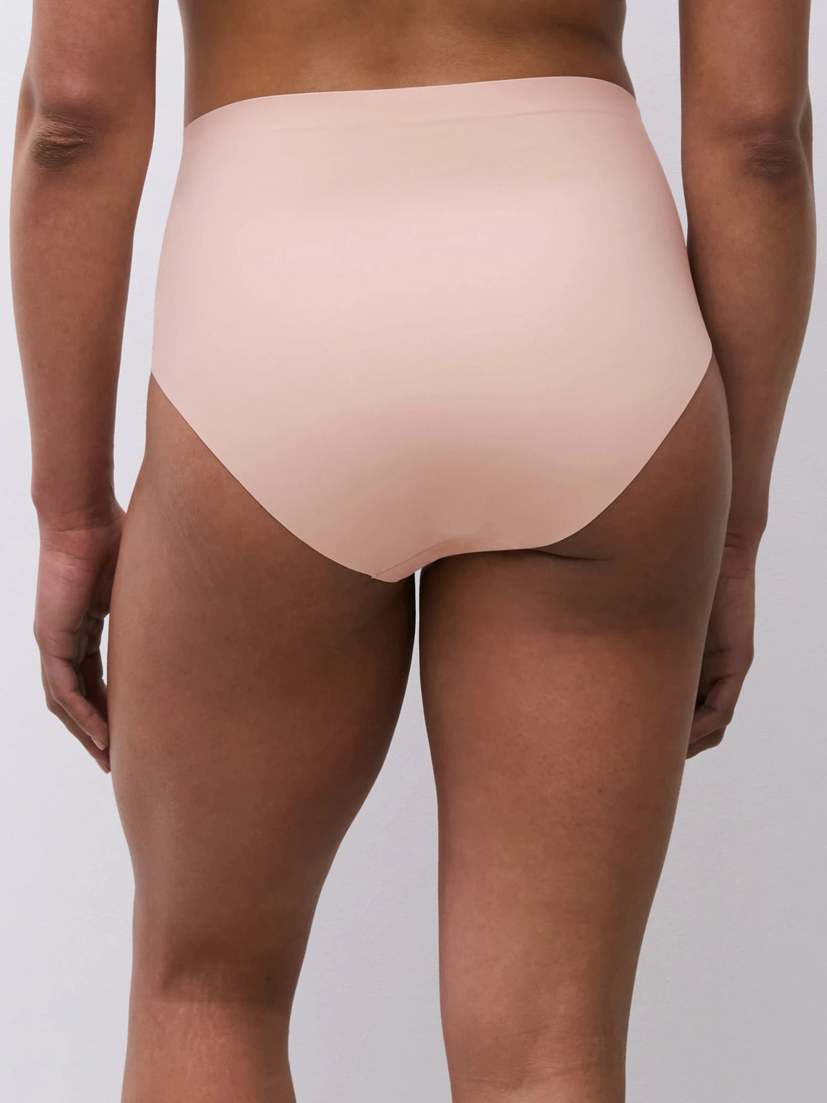 Person iført Chantelle Seamless - Defi Pudder 155790 trusser i nude, set bagfra på en ensfarvet baggrund.