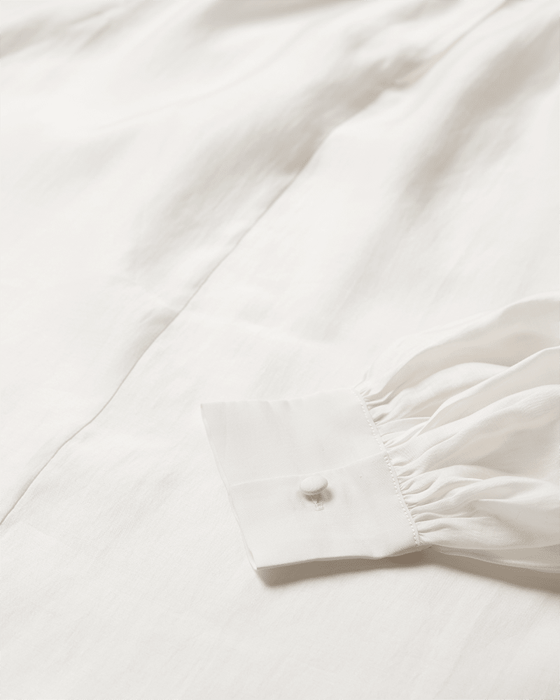 Nærbillede af Copenhagen Muse Molly Off – en offwhite bluse med ballonærmer, knapper på brystet og rynket stof.