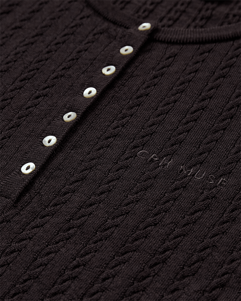 Nærbillede af Copenhagen Muse Eadie Kaffe-skjorten: mørk ribstrik, hvide knapper og broderet »Copenhagen Muse«-detalje.