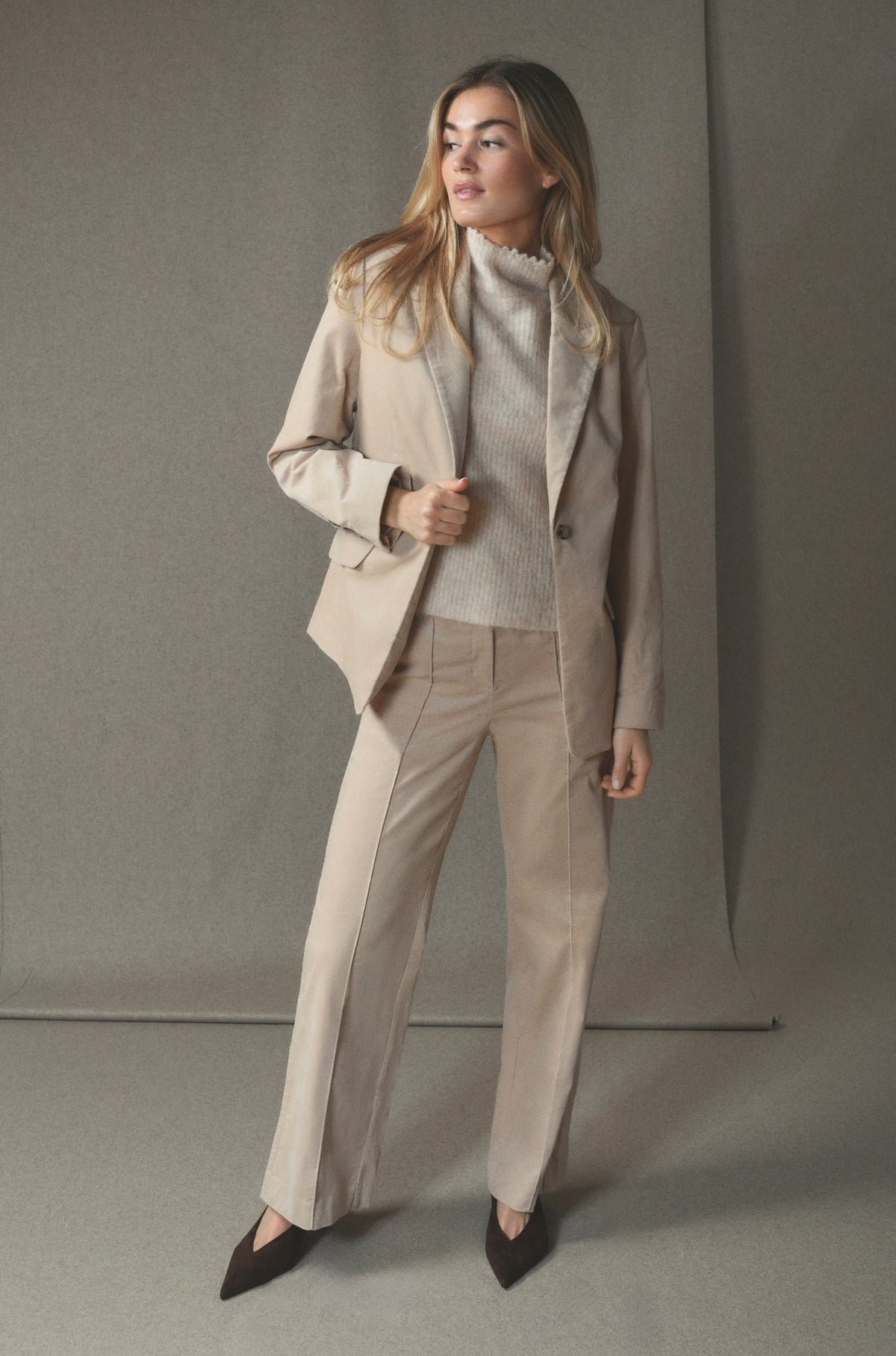 En person iført en 156409 | Gustav - Stacie Beige-blazer, matchende sweater og bukser samt mørke sko med spids snude.