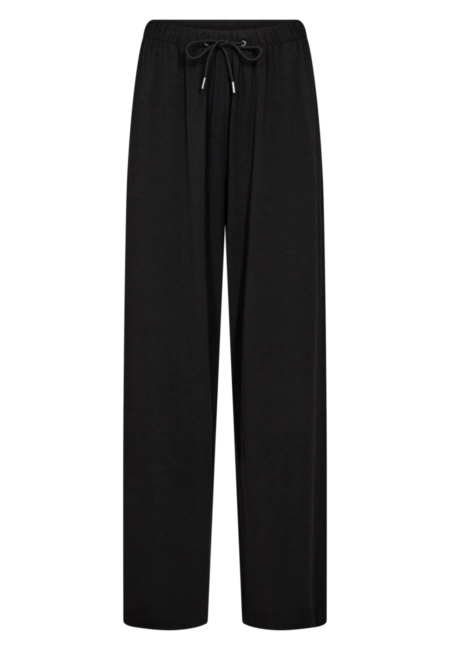 JBS of Denmark DK Bukser Sort: sorte loungewear-bukser med brede ben og snøre i taljen, vist på hvid baggrund.