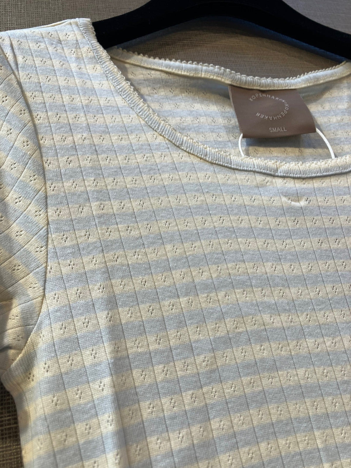 Nærbillede af Kopenhaken 154479 Soft T-shirt Lyseblå, størrelse small, diskrete striber, hvid ribbet bomuld på sort bøjle.