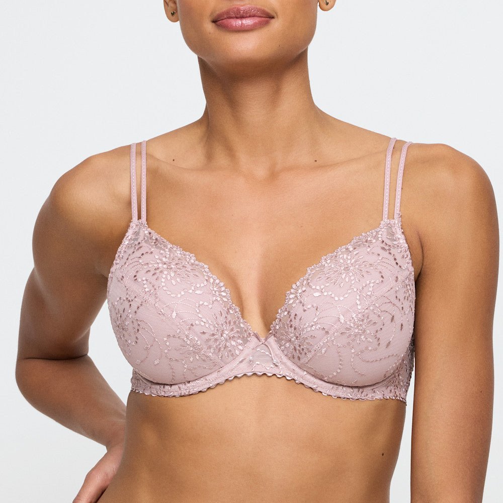 Kvinde iført en Marie Jo Jane Bois De Rose Rosa 144410-bh med tynde dobbelte stropper, foran en ensfarvet lys baggrund.