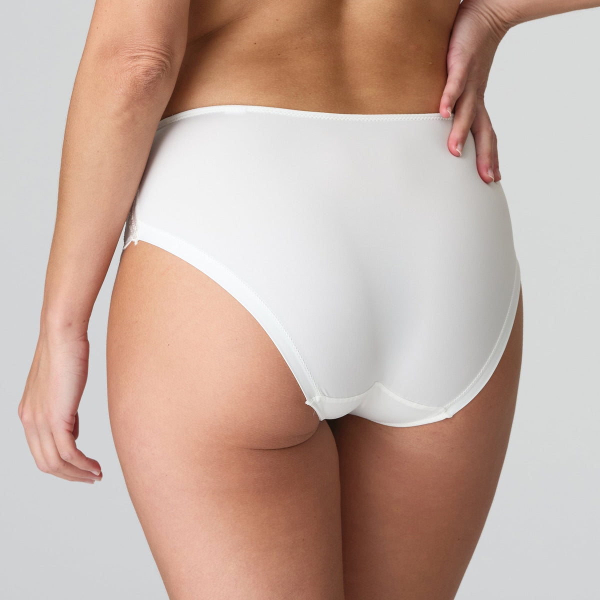 Person iført Marie Jo Heleen Natural Off White-maxi-trusse med høj talje, set bagfra med hånden på hoften.