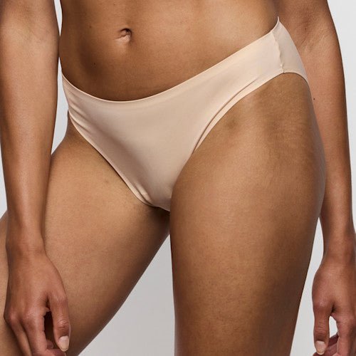 Model iført Marie Jo Soft Studio Caffe Latte Pudder-trusser, sømløse kanter, billede fra taljen til låret, neutral baggrund.