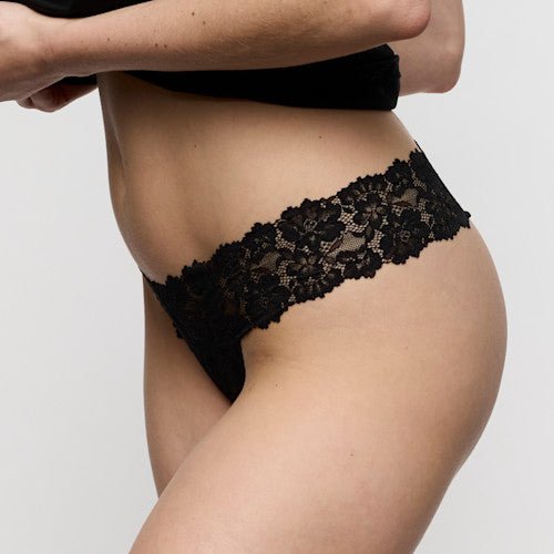 Modellen bærer Marie Jo - Soft Studio Black Sort-blonderundertøj, hvor overkroppen og armene ses tydeligt på en ensfarvet baggrund.