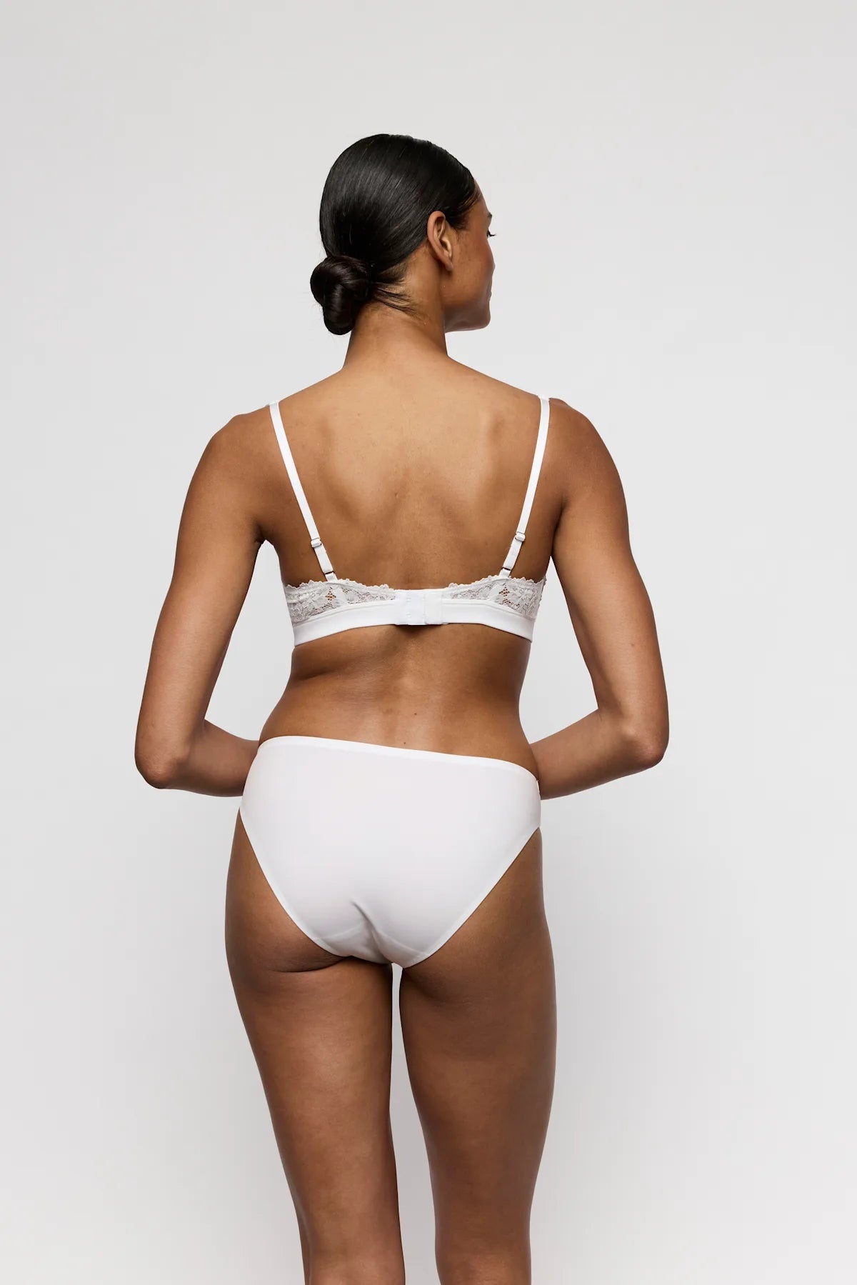 Kvinde iført et sæt fra Marie Jo – Soft Studio i offwhite, set bagfra, med sømløse kanter, på en ensfarvet lys baggrund.