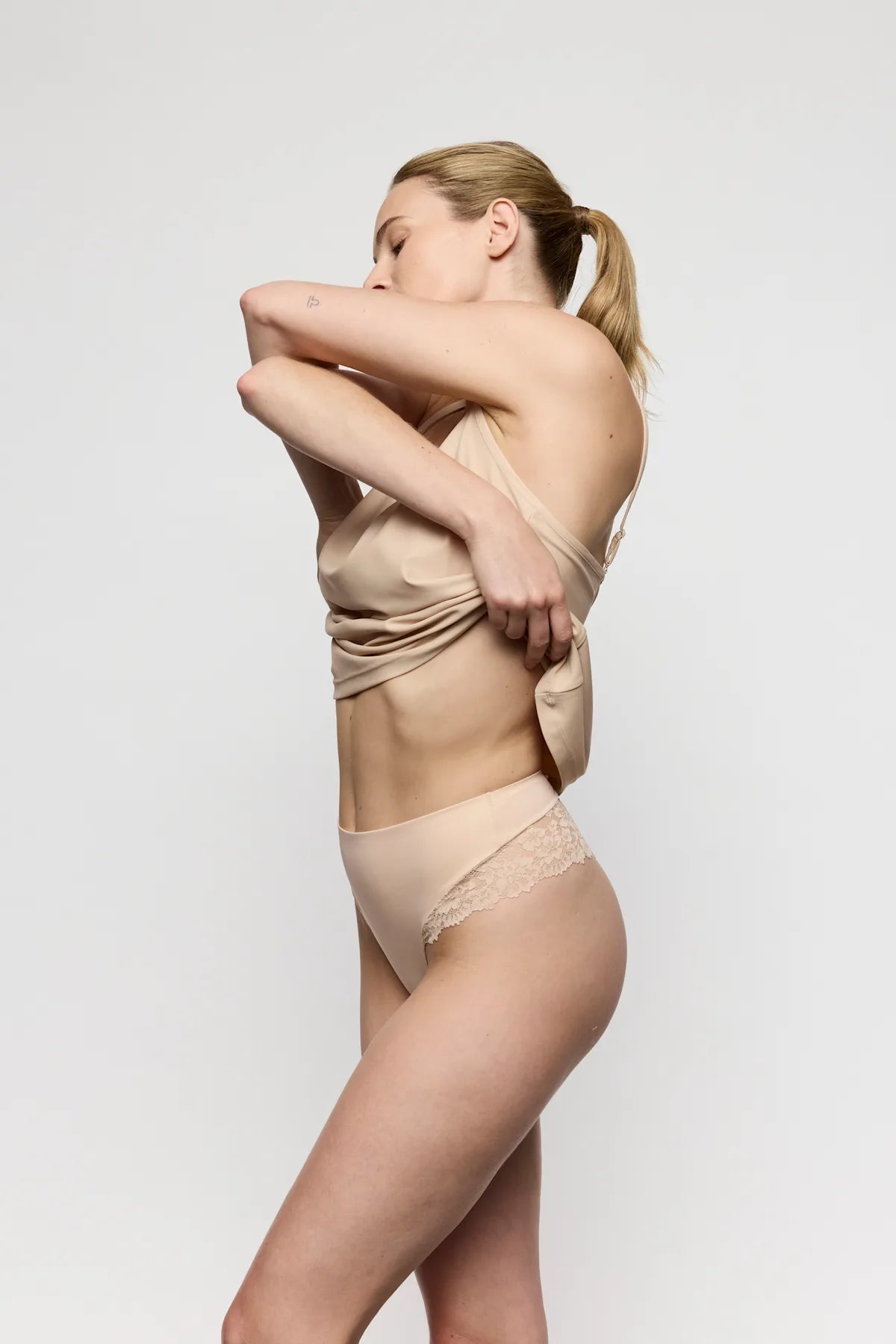 Kvinde iført Marie Jo Soft Studio Caffe Latte Pudder-undertøj med høj talje i blonde, der passer til den medfølgende top.