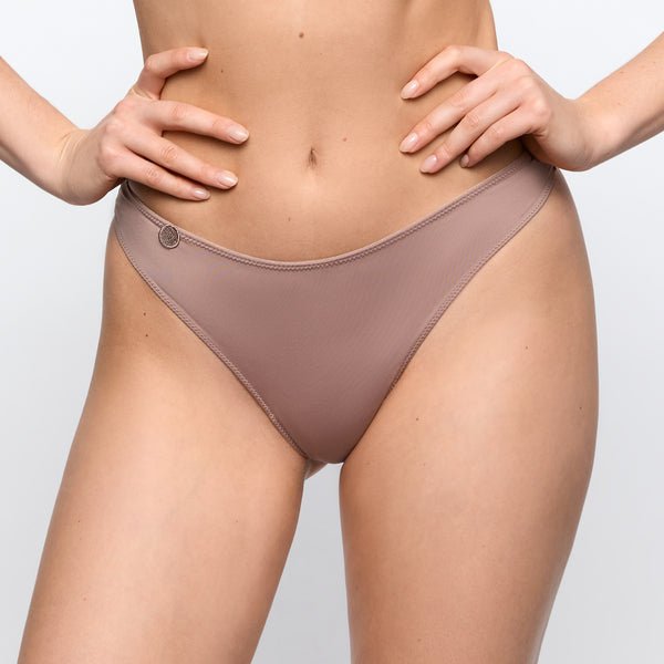 Model iført Marie Jo – Tom Cosmetic Lysebrun 155310, stående med hænderne i siden foran en ensfarvet, lys baggrund.