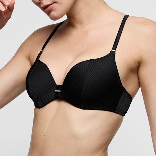 Model iført Marie Jo’s Cassie Black Sort-bikinitop med bøjle 155261 og tynde stropper foran en ensfarvet baggrund.