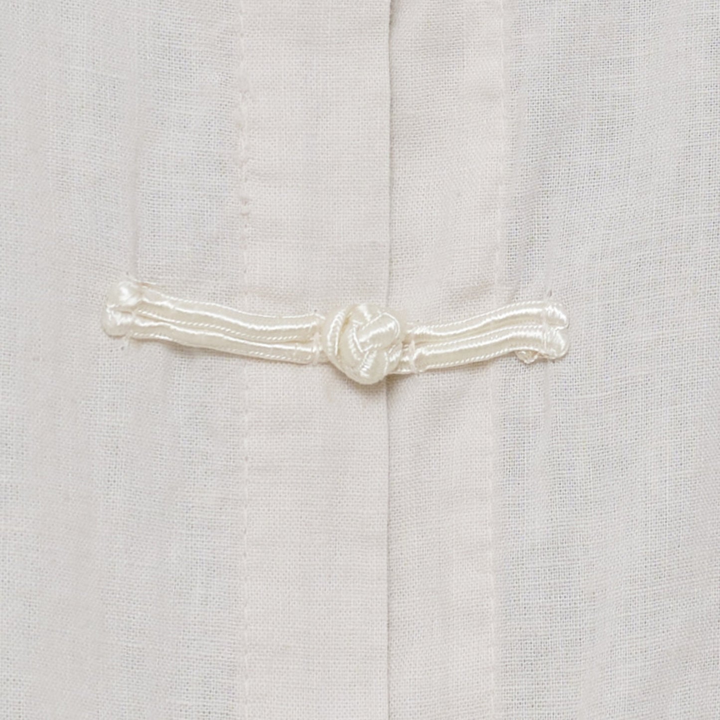 Nærbillede af Olina Beige-top fra Marta du Château med knudet knaplukning.
