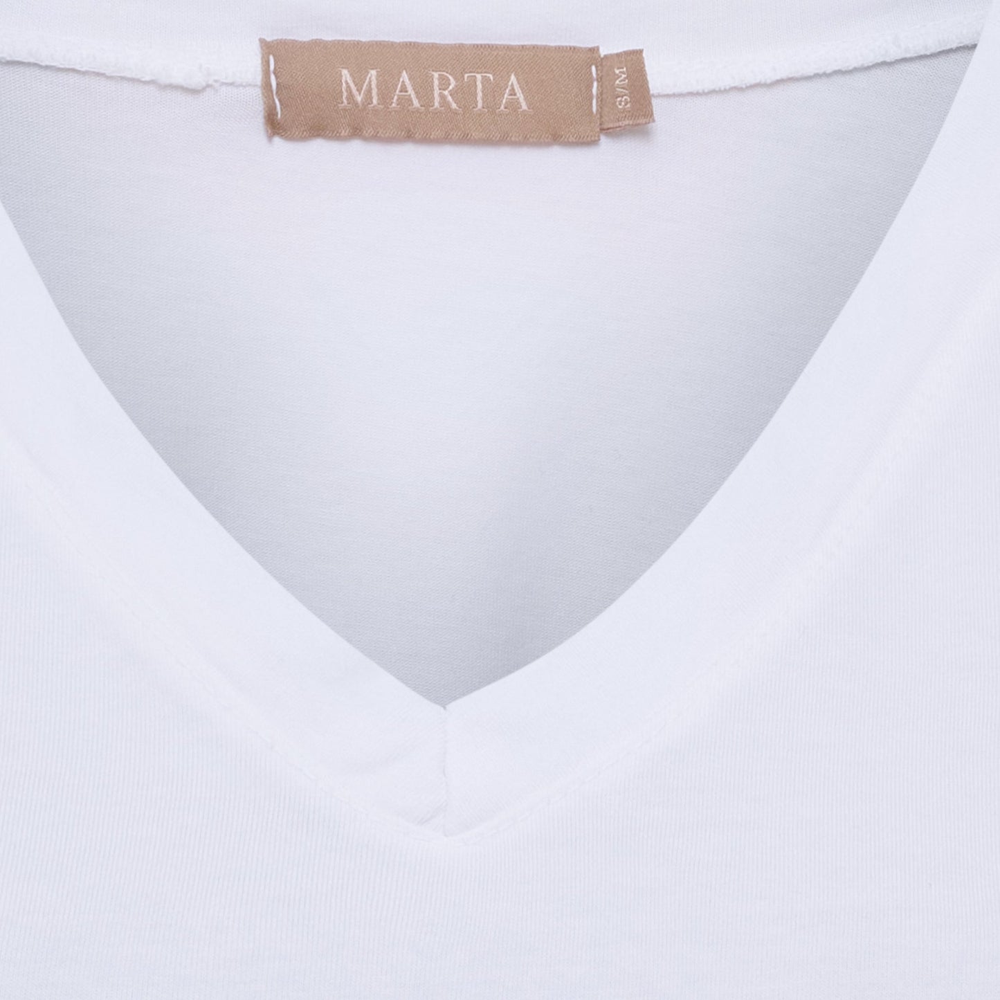 Nærbillede af Marta du Château Sabela Hvid T-shirt med V-udskæring, beige mærke, flæseærmer og størrelsesmærke S/M.