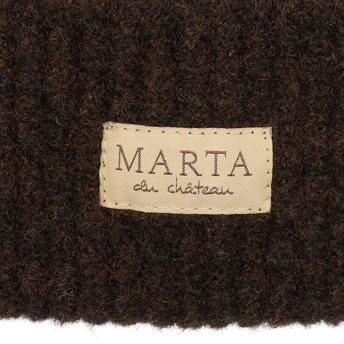 Et beige Marta du Château - MDCDelie Brun-mærke placeret midt på et mørkebrunt strikstof med struktur.