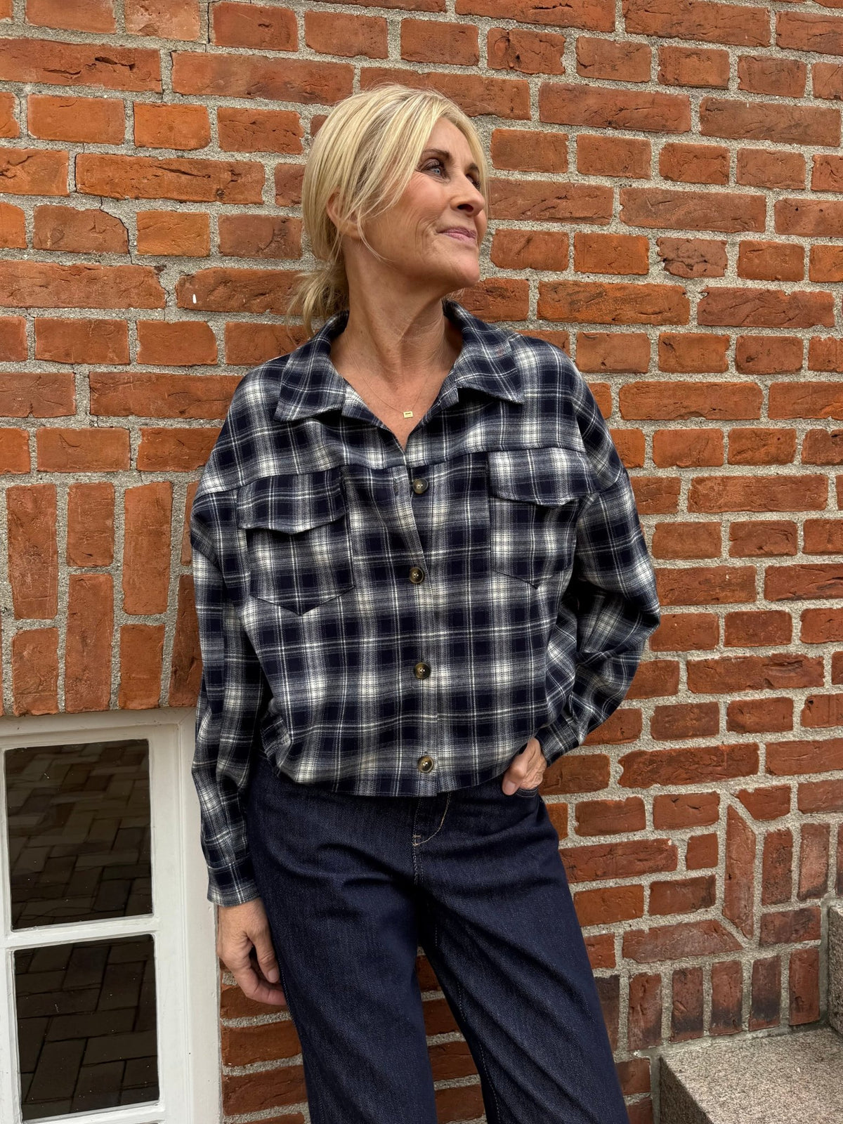 En kvinde iført en 156371 | Marta du Château - MDCMarbella mørkeblå ternet skjorte og mørke denimjeans.