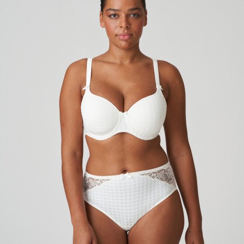 En kvinde iført en off-white bh og et maxitrusse fra PrimaDonna Madison står foran en ensfarvet baggrund.