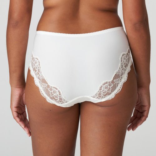 En person iført PrimaDonna Madison Natur Off-white maxitrusse, set bagfra på en ensfarvet baggrund.