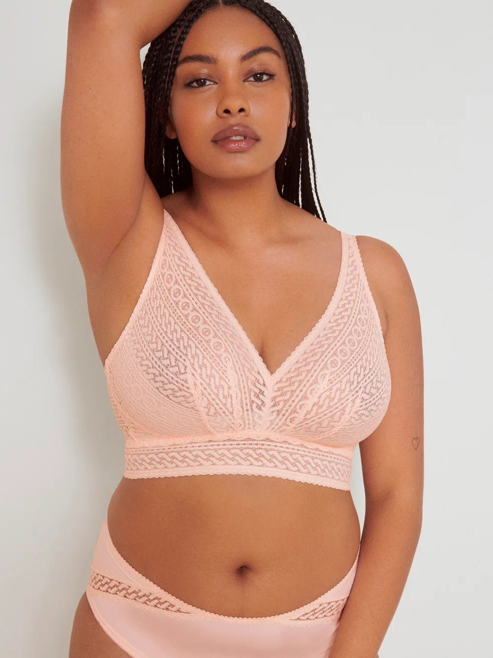 Kvinde iført en PrimaDonna Montara Crystal Pink Rosa-bralette, med den ene arm løftet, fotograferet foran en ensfarvet baggrund.