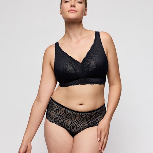 En kvinde iført en PrimaDonna Salerno Midnight Blue-bralette står foran en ensfarvet lys baggrund.