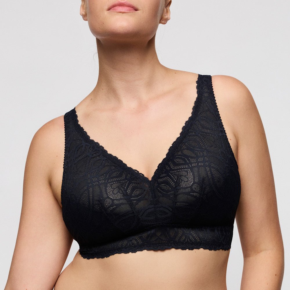 Model iført PrimaDonna Salerno Midnight Blue 151788 bralette, vist fra skuldrene til midten af overkroppen på en ensfarvet baggrund.