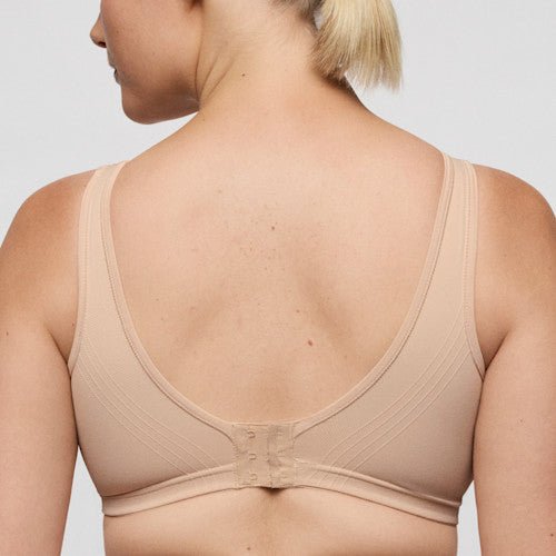 Kvinde set bagfra iført en PrimaDonna Nudda Caffe Latte Pudder-bh med brede stropper, sømløst design og ensfarvet baggrund.