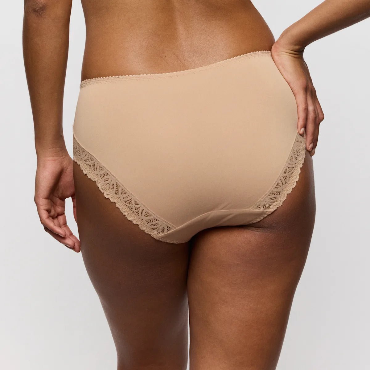 Model iført PrimaDonna Salerno Candy Ginger Pudder 154832 maxi-trusser, set bagfra på en ensfarvet lys baggrund.