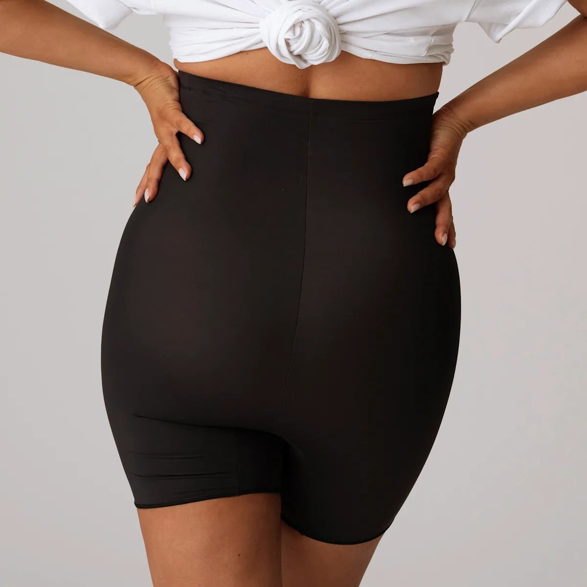 Modellen, der bærer PrimaDonna Perle Charcoal-shapewear, ses bagfra, hvilket giver en glat silhuet og en sømløs truseeffekt.