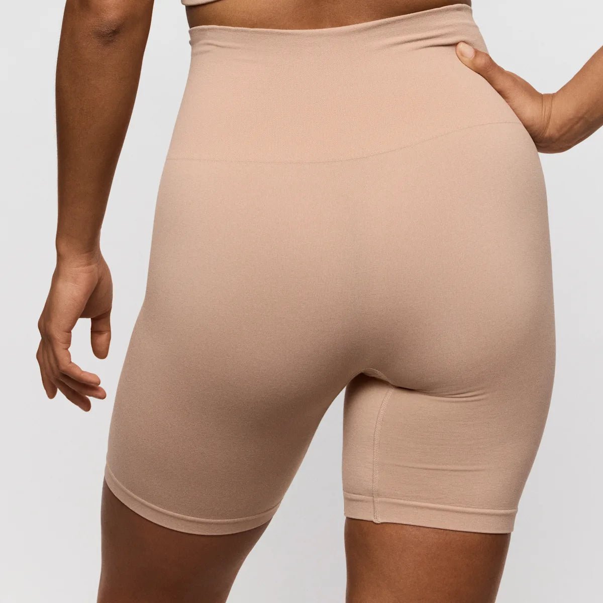 En person iført PrimaDonna Nudda Caffe Latte Pudder-bikershorts med høj talje og uden søm, set bagfra foran en enkel baggrund.