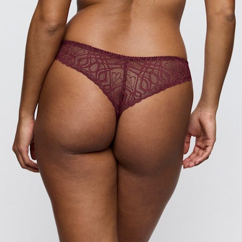 Modellen bærer PrimaDonna 155416 G-streng i farven »Evening Red Bordeaux«, vist bagfra på en ensfarvet lysegrå baggrund.