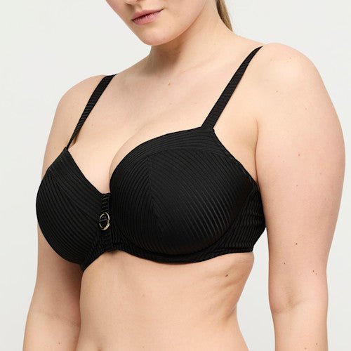 En person har PrimaDonnas Delray Black bikini-overdel med bøjle på, der er prydet med en metal-detalje, der giver et eksklusivt look.