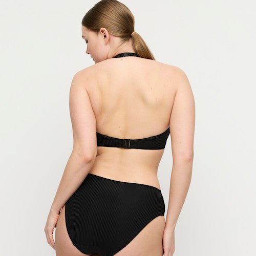 En kvinde med lys hud bærer PrimaDonna Swim – Delray Black Sort, set bagfra på en ensfarvet baggrund.