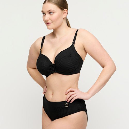 Kvinde i en sort bikini fra PrimaDonna Swim Delray, med struktureret stof, metalliske ringe og et design, der giver god støtte.