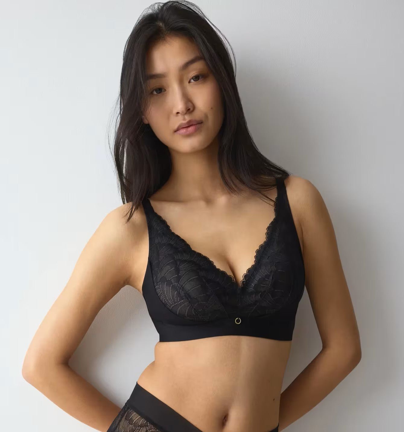 Model iført sort bralette og underdel fra Triumph Love In Lace 0004, fotograferet foran en hvid baggrund.