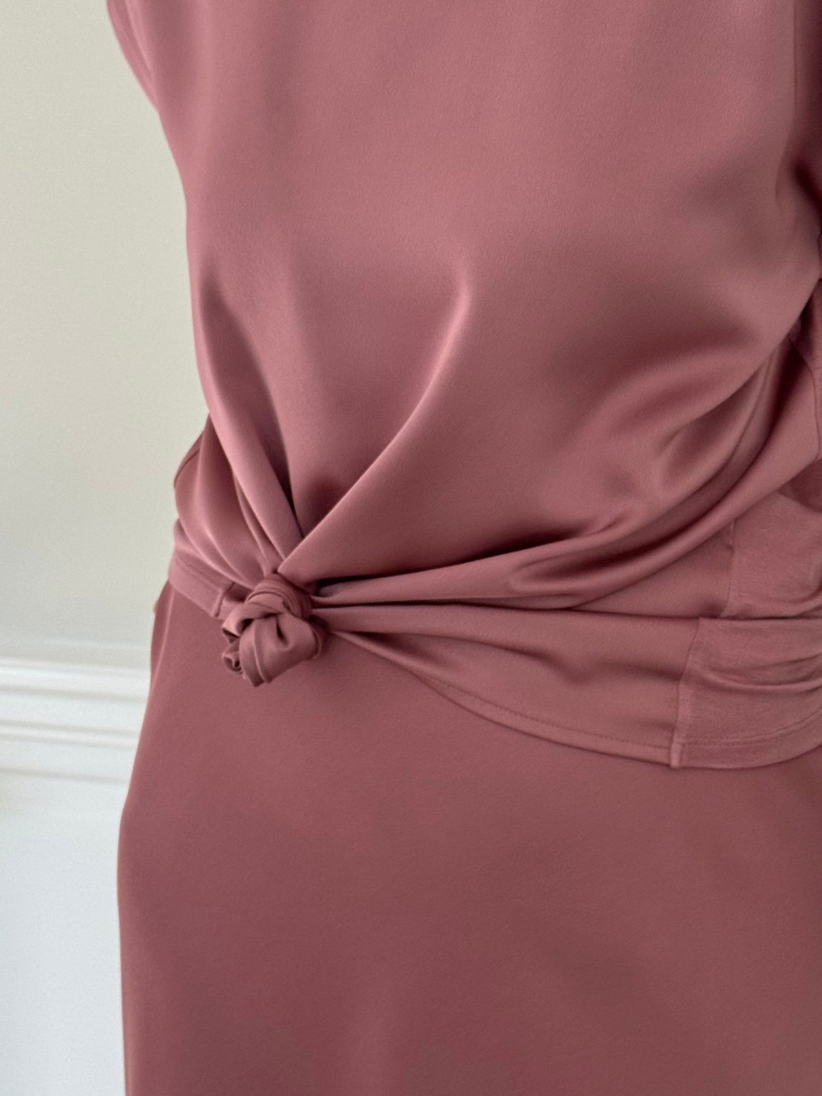 En person iført en VILA Viellette Rosa-top, der er bundet bagpå, står foran en neutral væg.