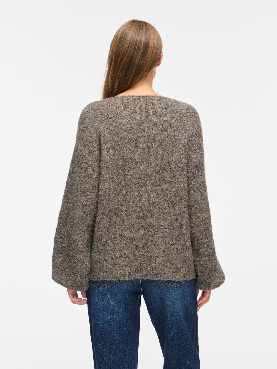 En person, der står med ryggen til, iført en brunmeleret VILA Vimarley-bluse med lange ærmer og blå jeans på en hvid baggrund.