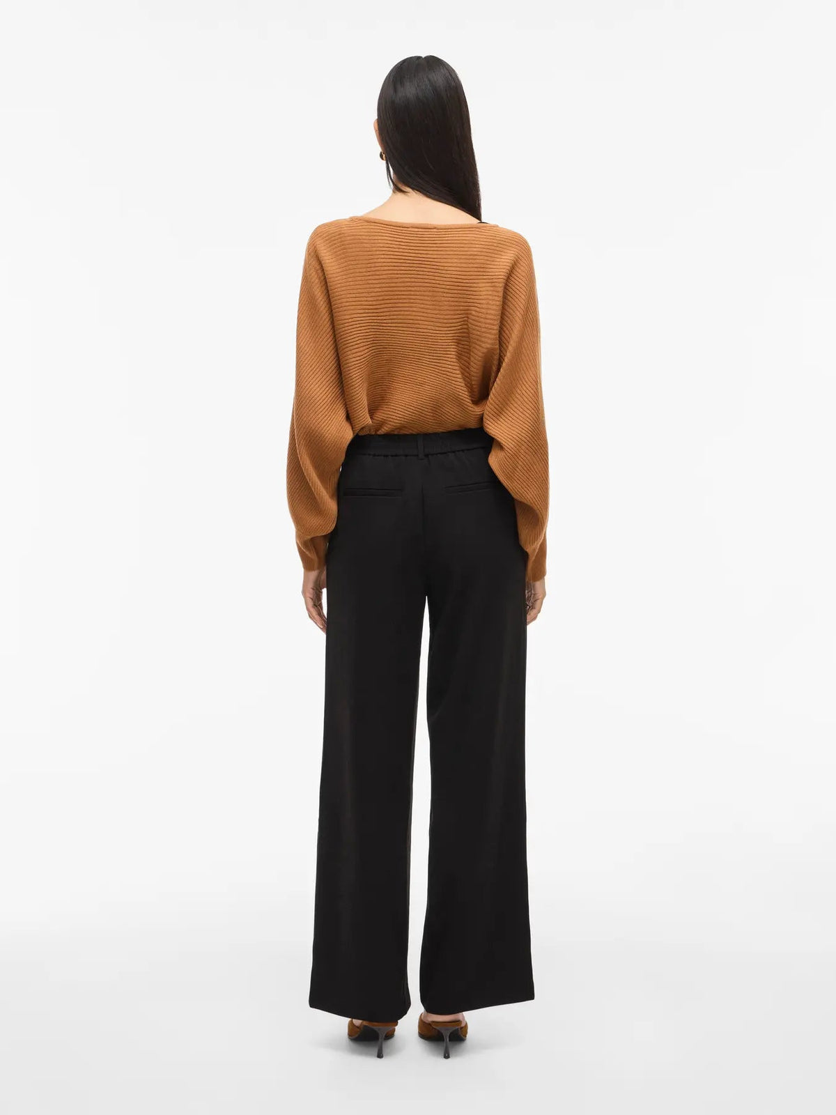 Kvinde i VILA – Varone: Sorte bukser og brun sweater, kombineret med hæle for et elegant, klassisk look.