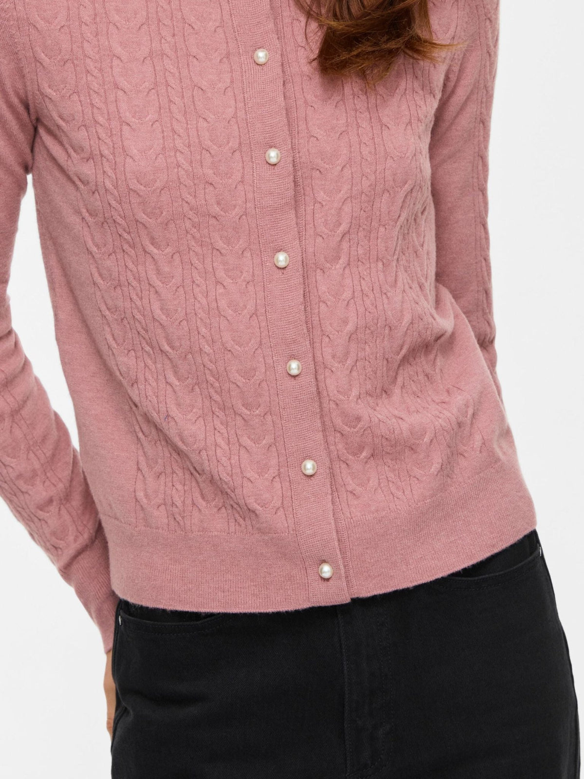 Kvinde iført en VILA Vikerry-cardigan i gammelrosa med perleknapper og snoningsmønster, kombineret med en sort nederdel.