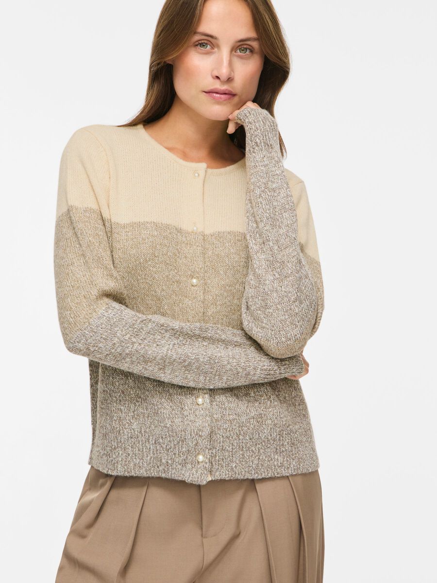 En kvinde har en beige og brun VILA - VISposa Stribet strikket cardigan med farveblokke og perleknapper på.