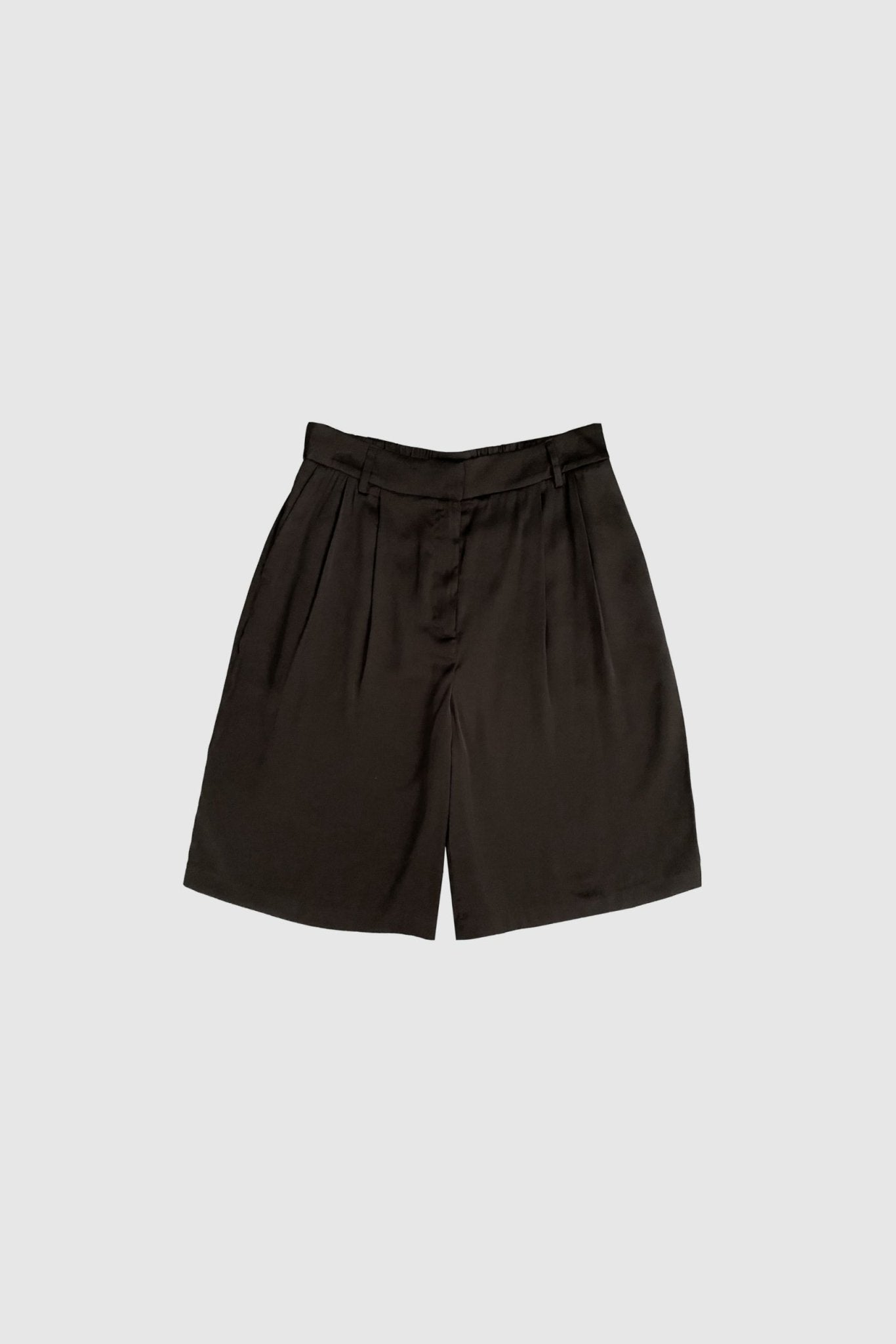 WithBlack – Paddie Mørkebrun: Shorts med høj talje, løs pasform og brede ben samt læg på en ensfarvet lysegrå baggrund.