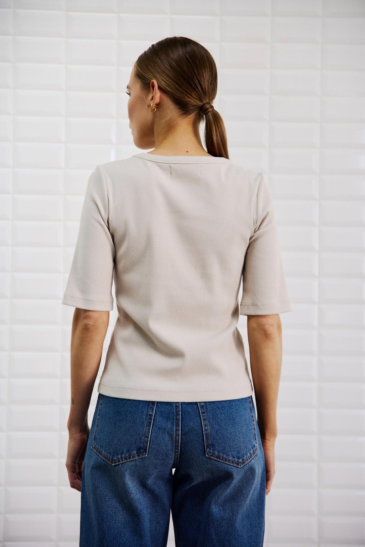 Bagfra-billede af en person, der bærer en beige 157657 | WithBlack - WBLLullu Beige T-shirt med rund hals og blå jeans.