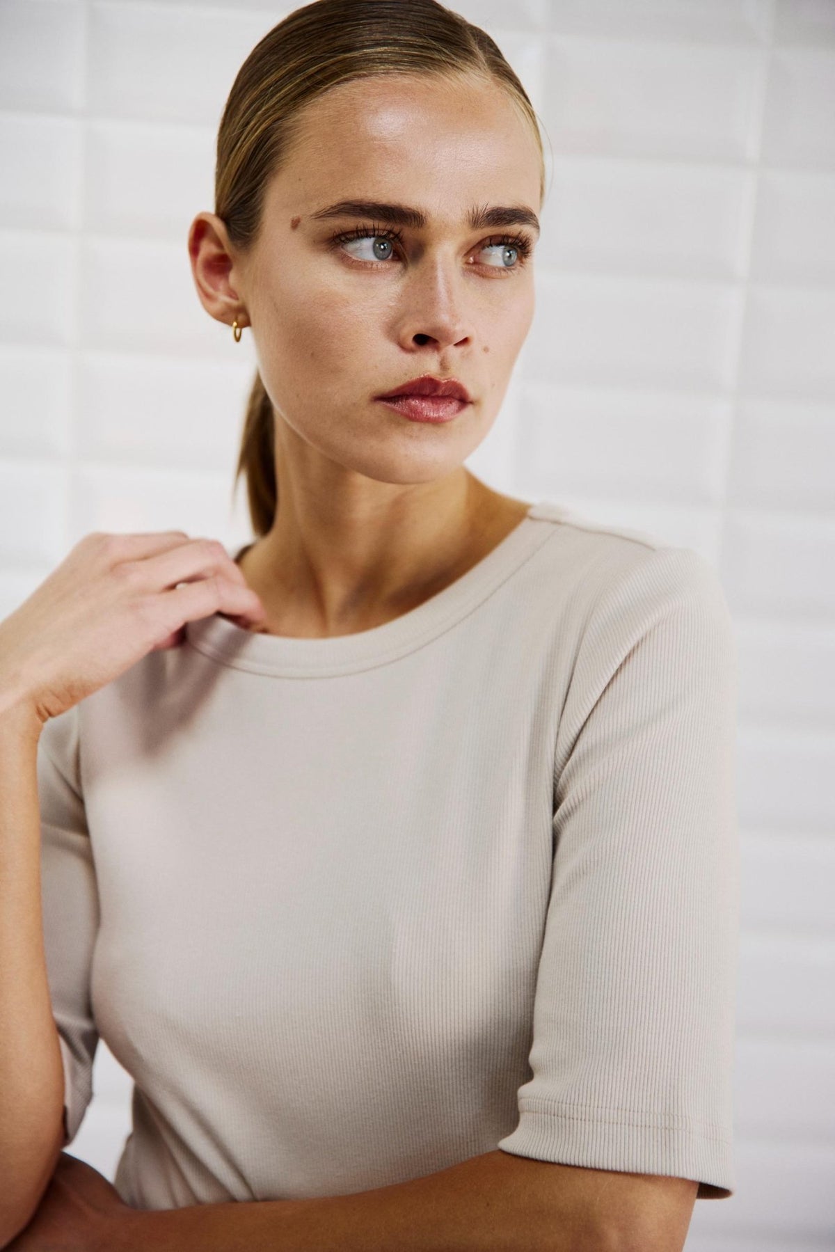 Kvinde iført en WithBlack 157657 WBLLullu beige ribbet bluse med rund hals.